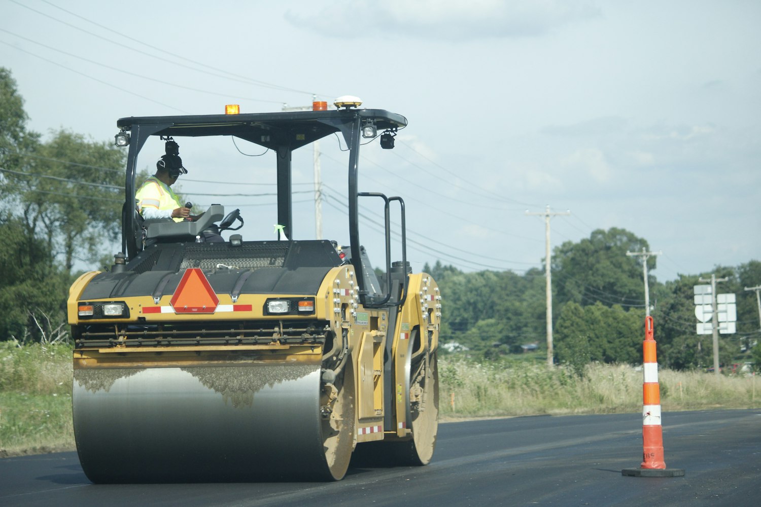 Asphalt roller compacting a fresh full-depth base install in daylight